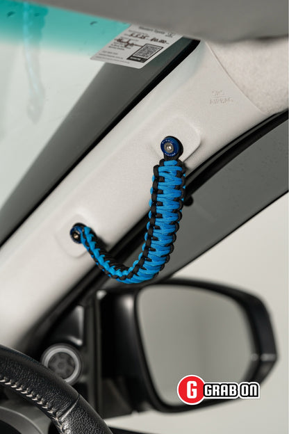 Blue braided carabiner attached to a car's interior door handle with Grabon branding.