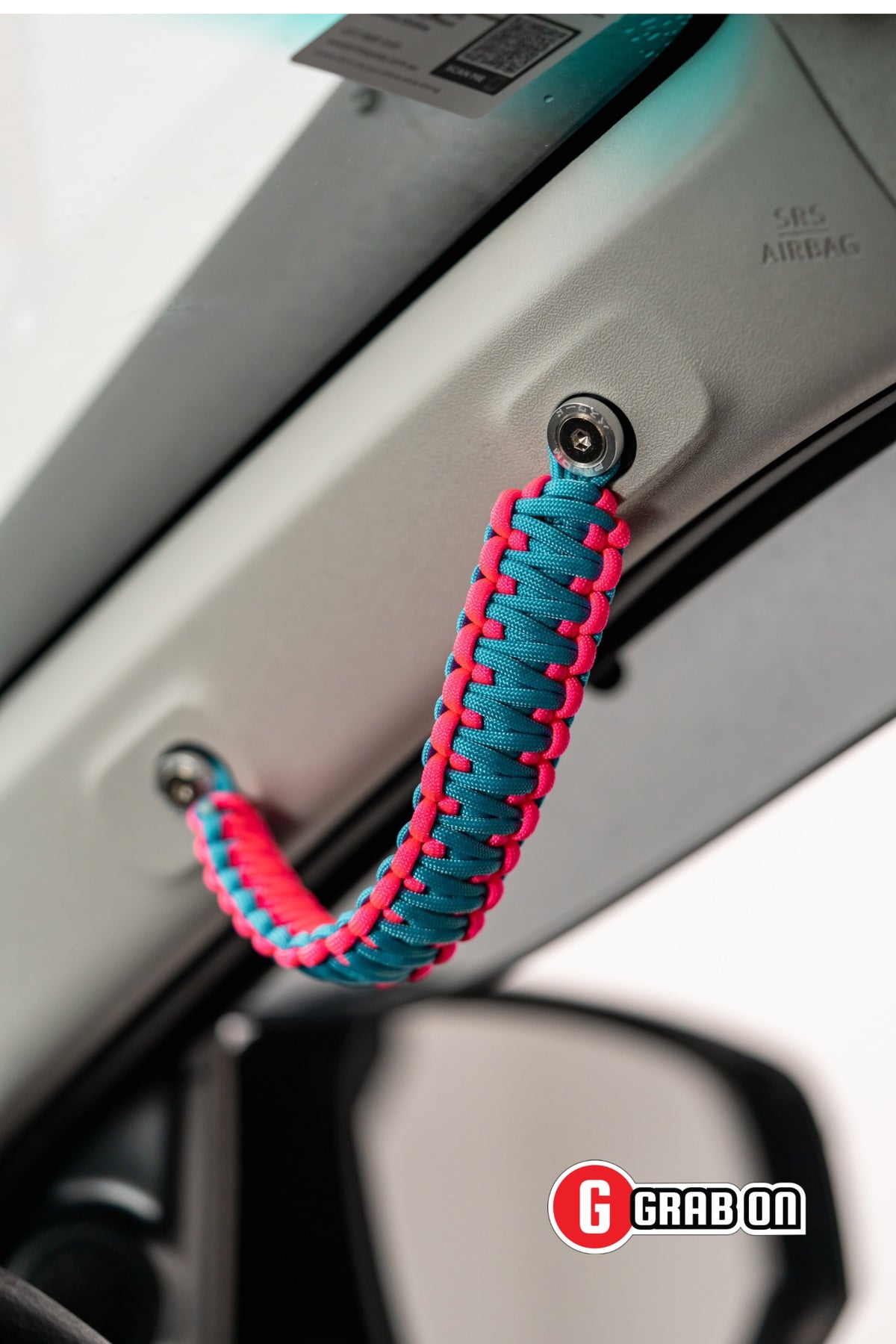 Paracord handle attached to a car's interior door panel with Grabon branding.